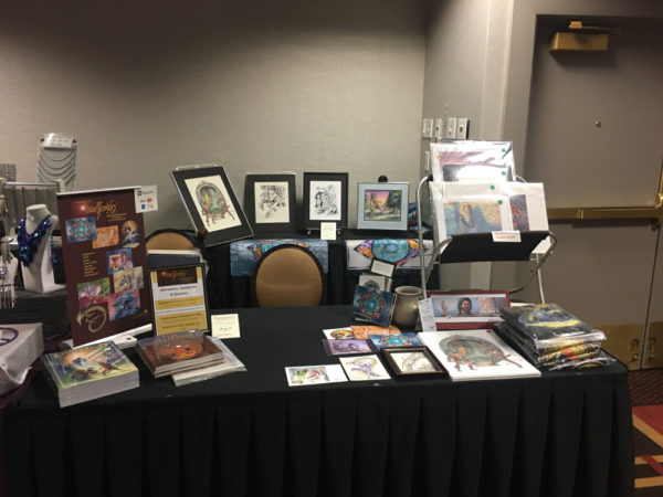 A table with art and books for sale on display.