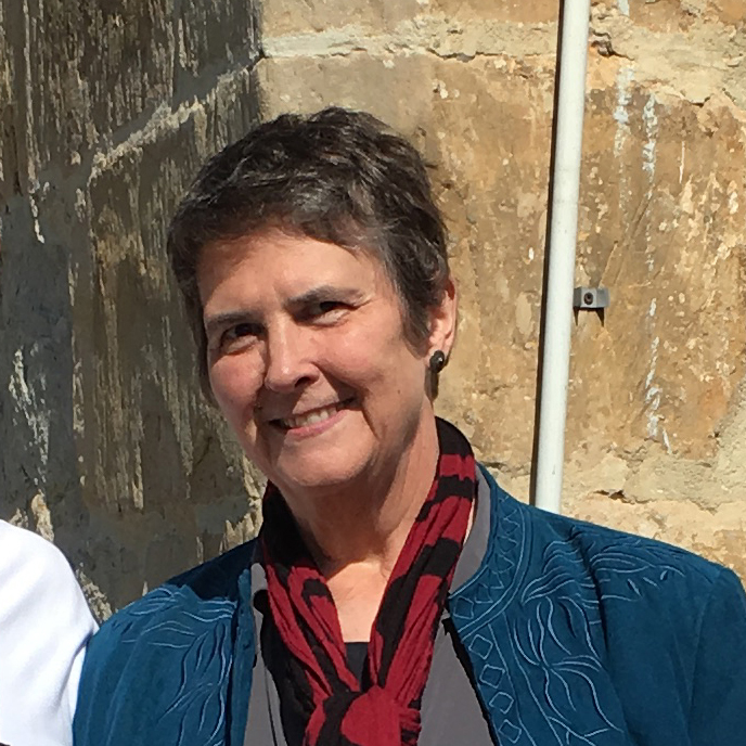 A smiling woman Liz Danforth in a blue coat and red scarf.